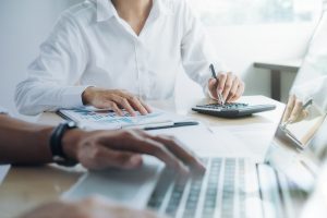 Réunion d’affaires avec des professionnels analysant des graphiques financiers et utilisant une calculatrice et un ordinateur portable pour planifier un nouveau projet d’investissement.